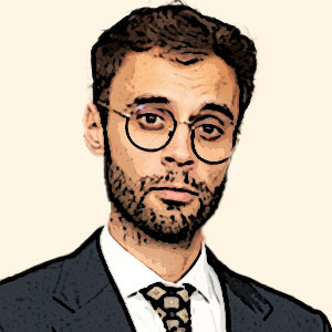 Hombre joven con barba, gafas y traje oscuro, expresión seria.